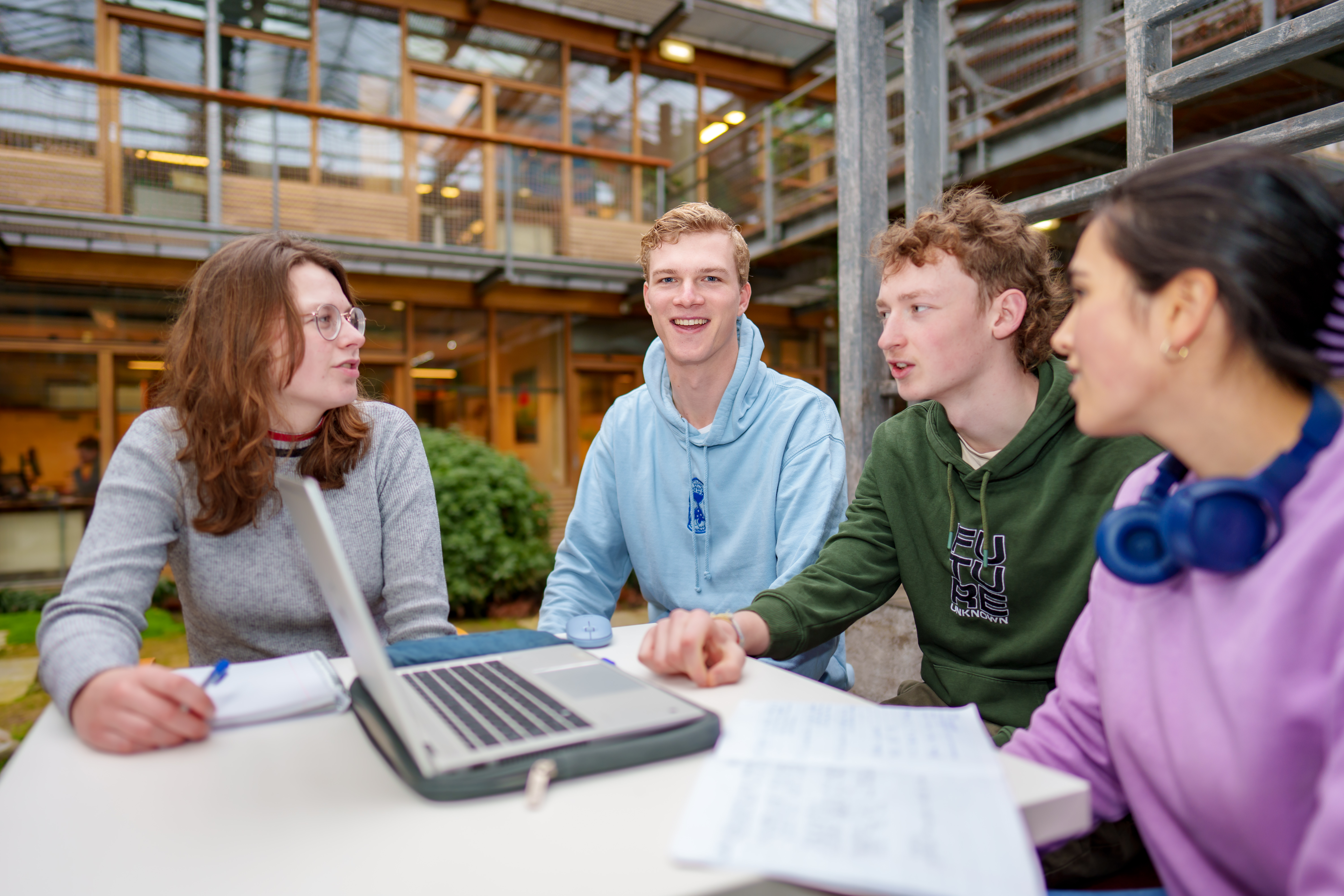 Mathijs, bachelor student  International Land and Water Management at a table with other students talking in Lumion garden building