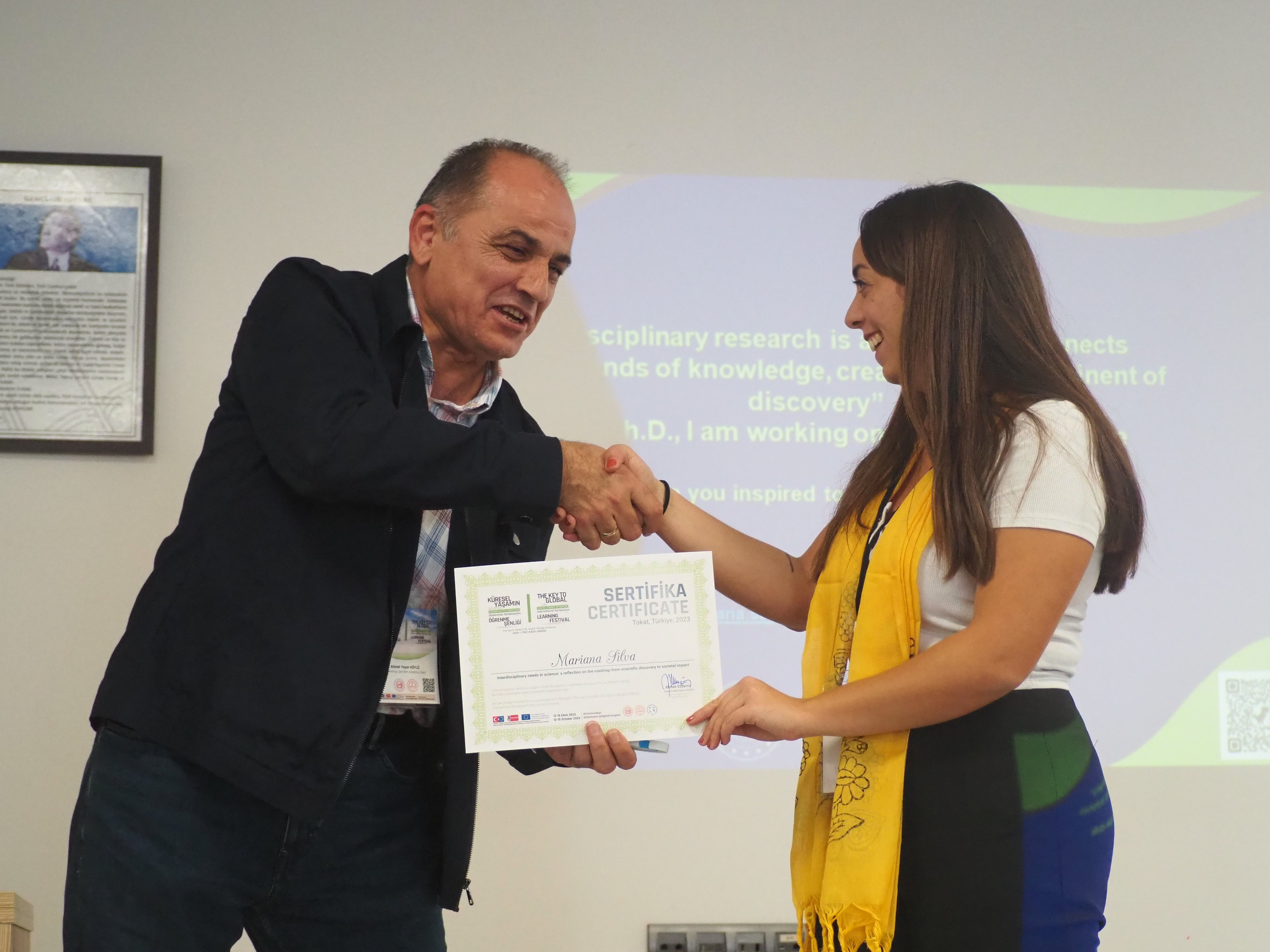 Mariana Santos die haar certifcaat ontvangt. Ze schudt meet de man die het haar overhandigt.