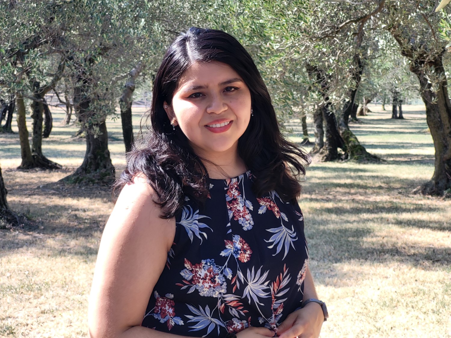 Wendy Cevallos smiling for the camera. She is standing in an orchard.