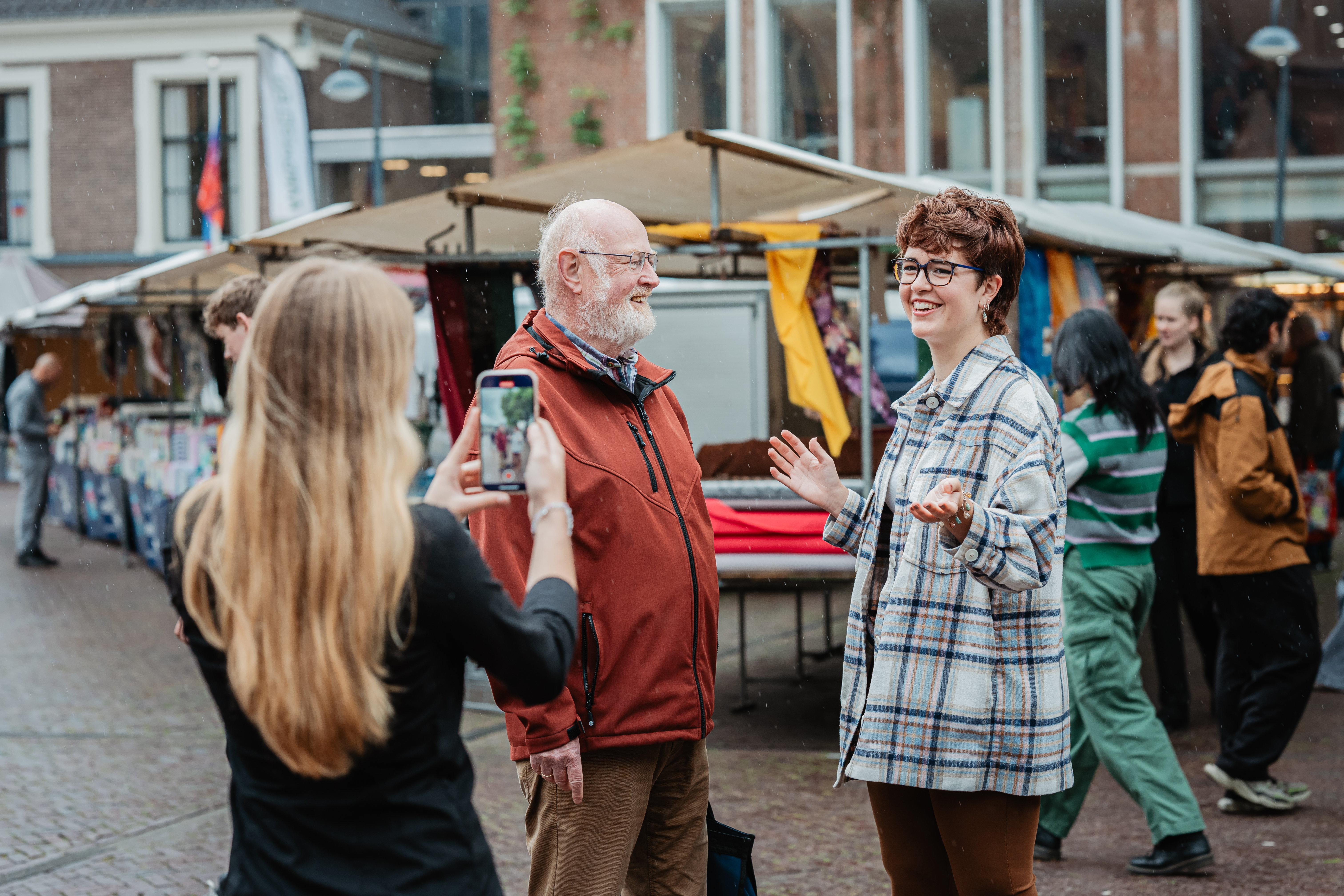 vrouw maakt filmpje van een gesprek tussen twee mensen