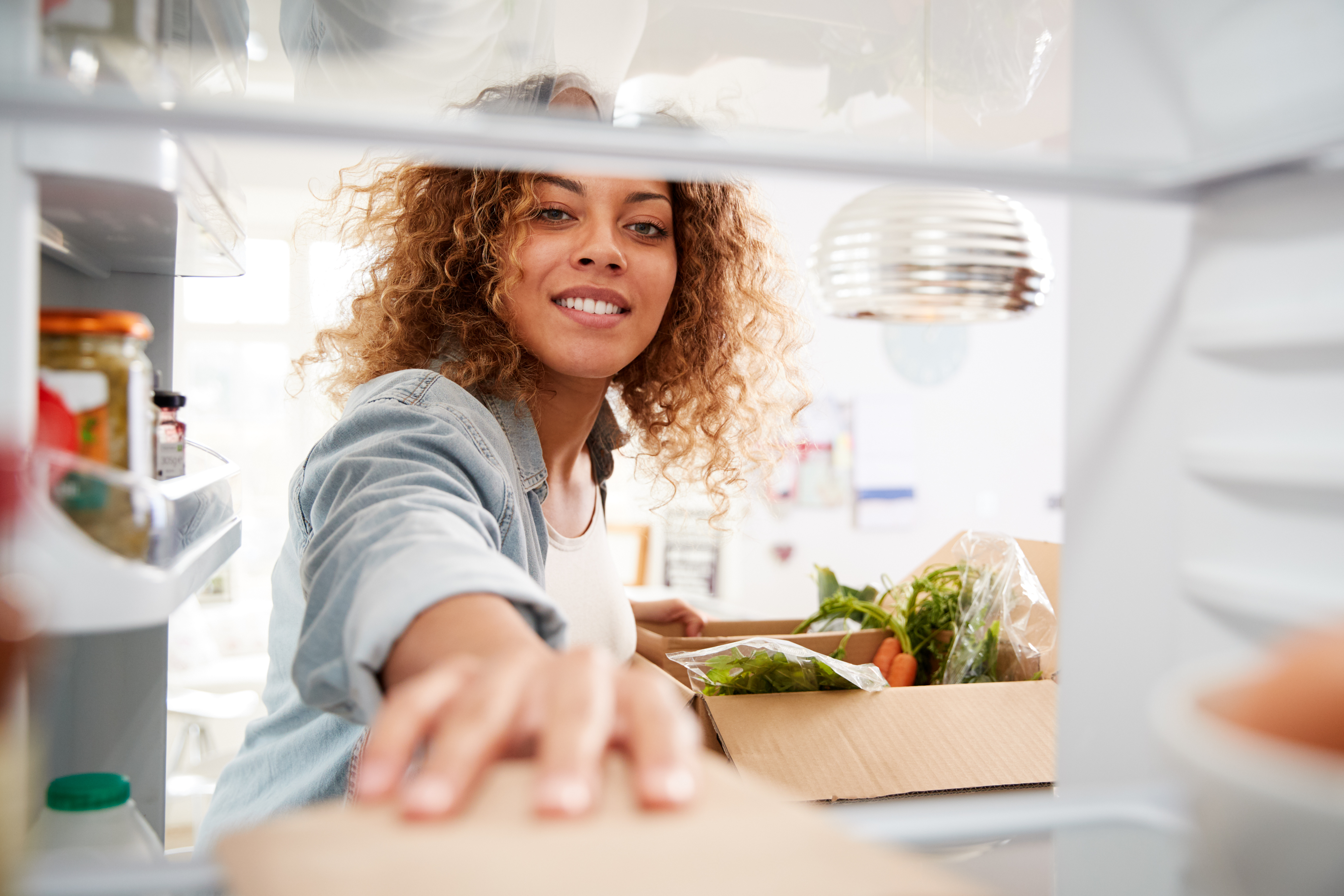Woman grabs box of food from a fridge