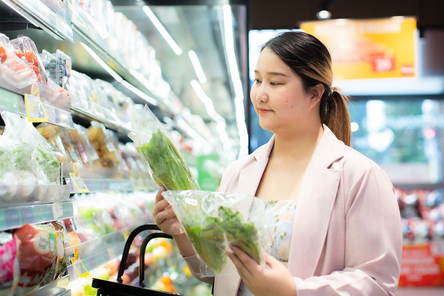 A women in a supermarket shopping for vegetables