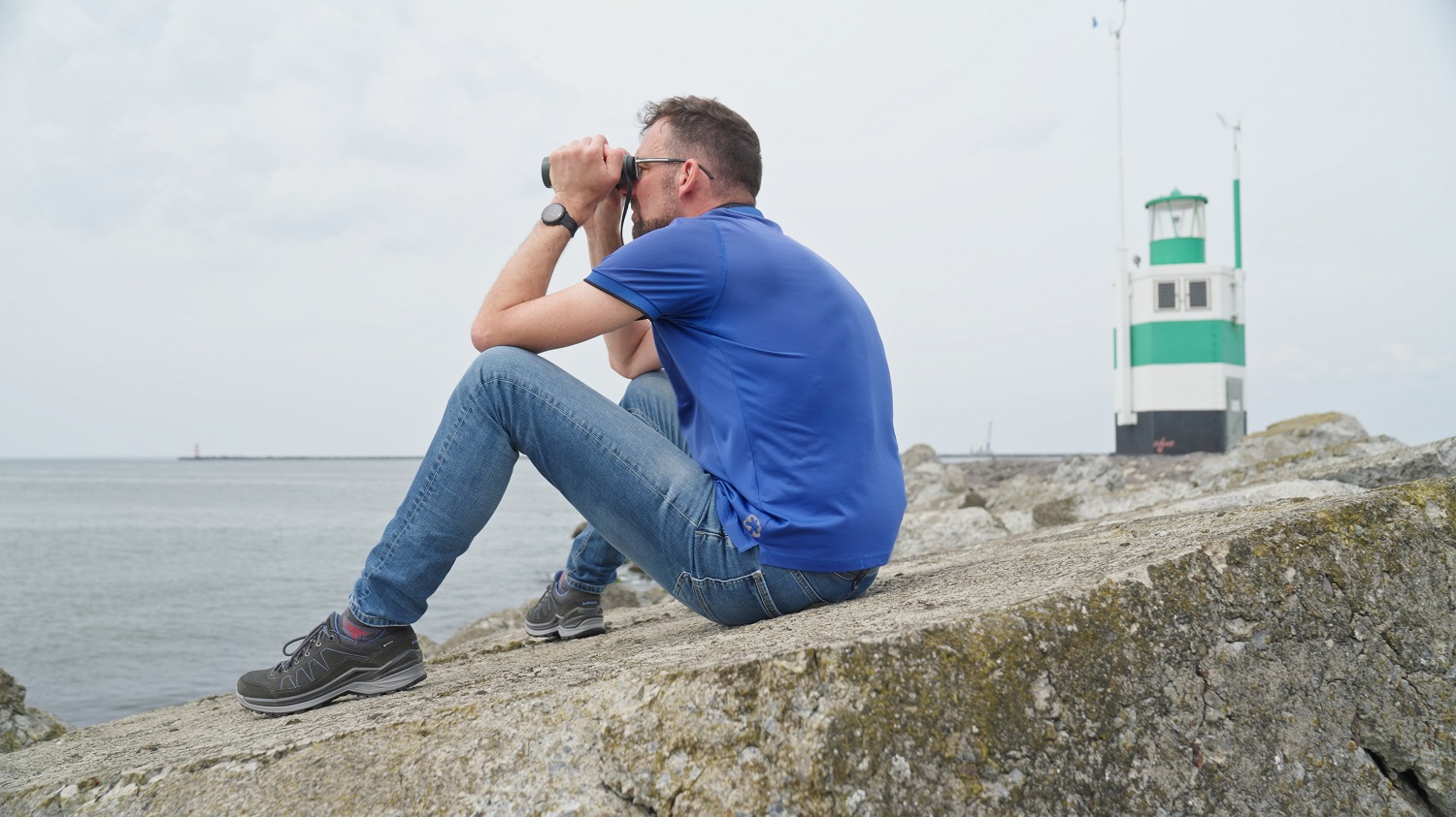 Man tuurt door verrekijker naar de zee