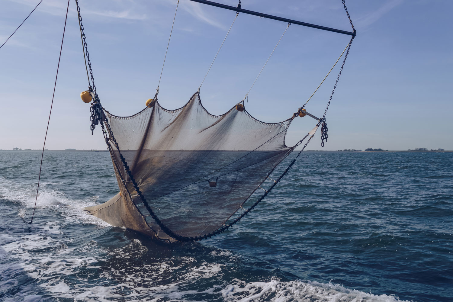Foto van een bodemsleepnet dat uit het water wordt gehaald