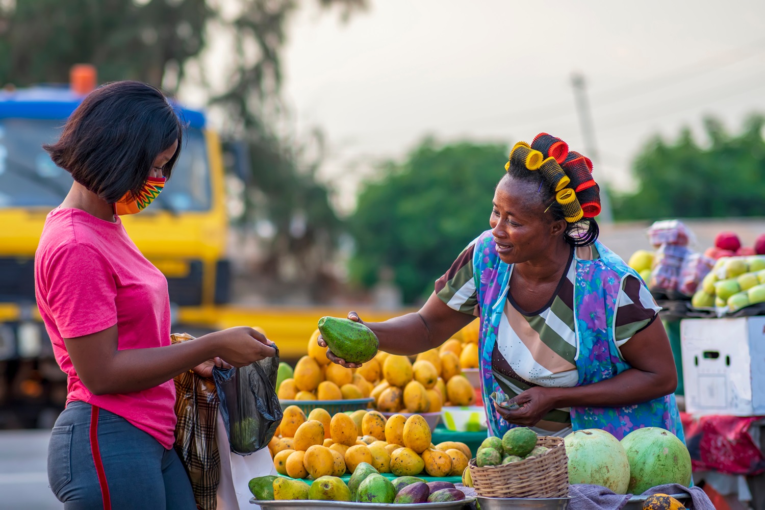Afrikaanse vrouw koopt fruit bij kraampje