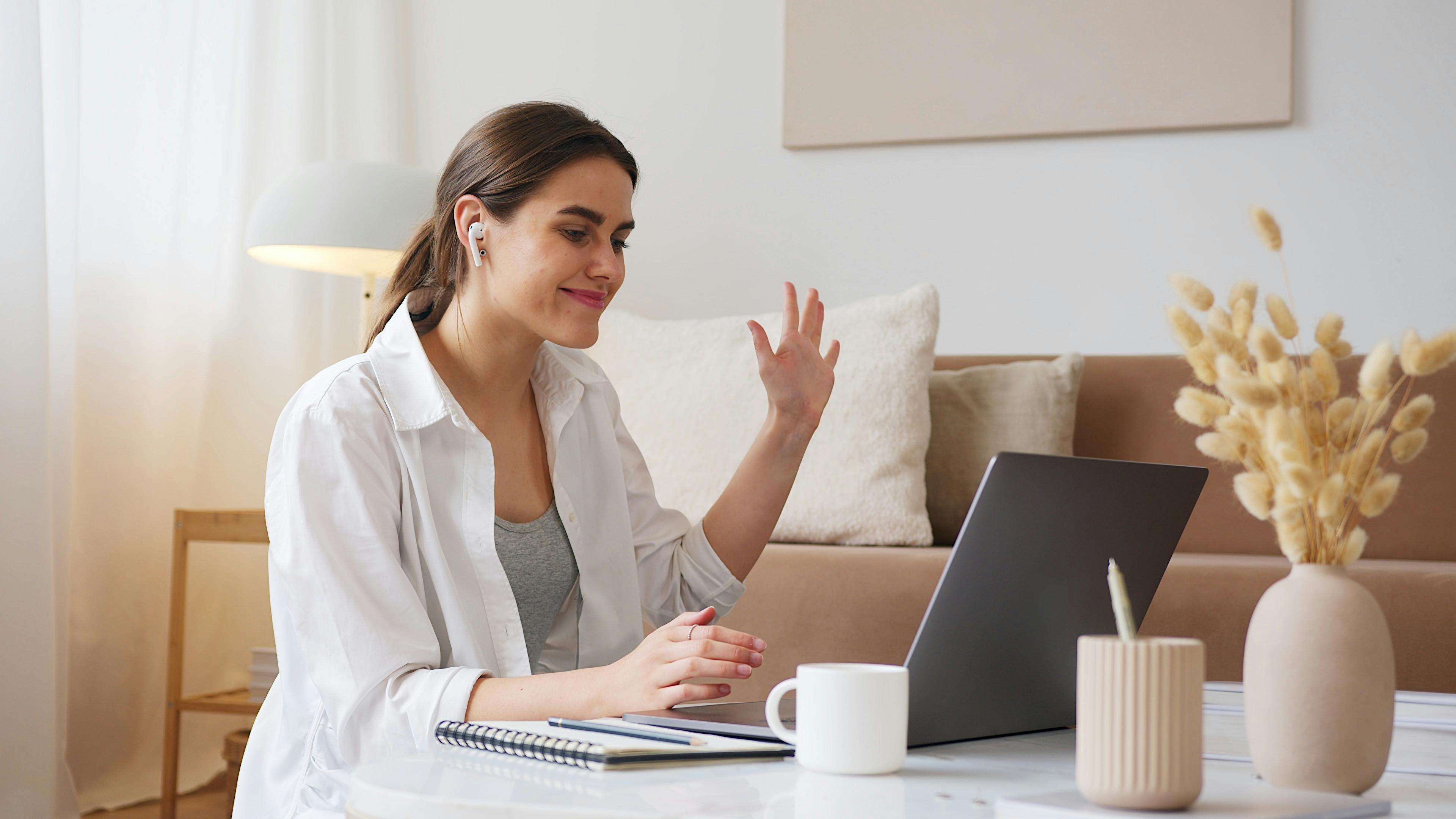 Vrouw zwaait naar haar laptopscherm