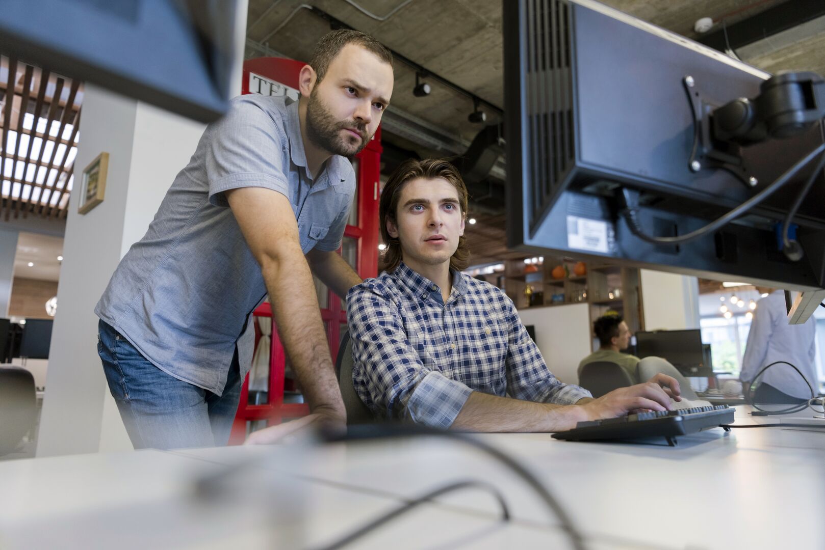 Twee mannen zitten achter de computer en kijken naar het scherm