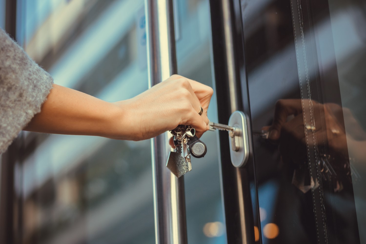 A close up of a hand pushing a key in the lock of a front door