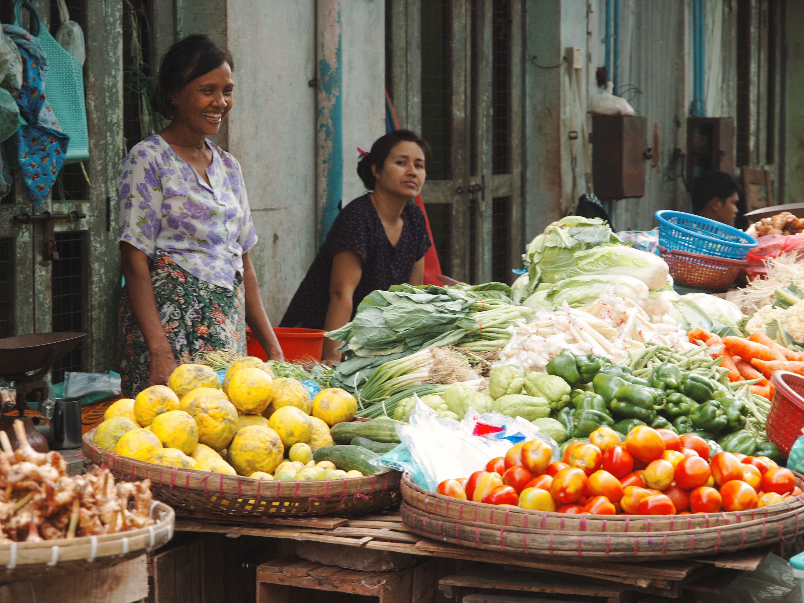 Young Burmese women selling fresh fruits and vegetables in the street market.