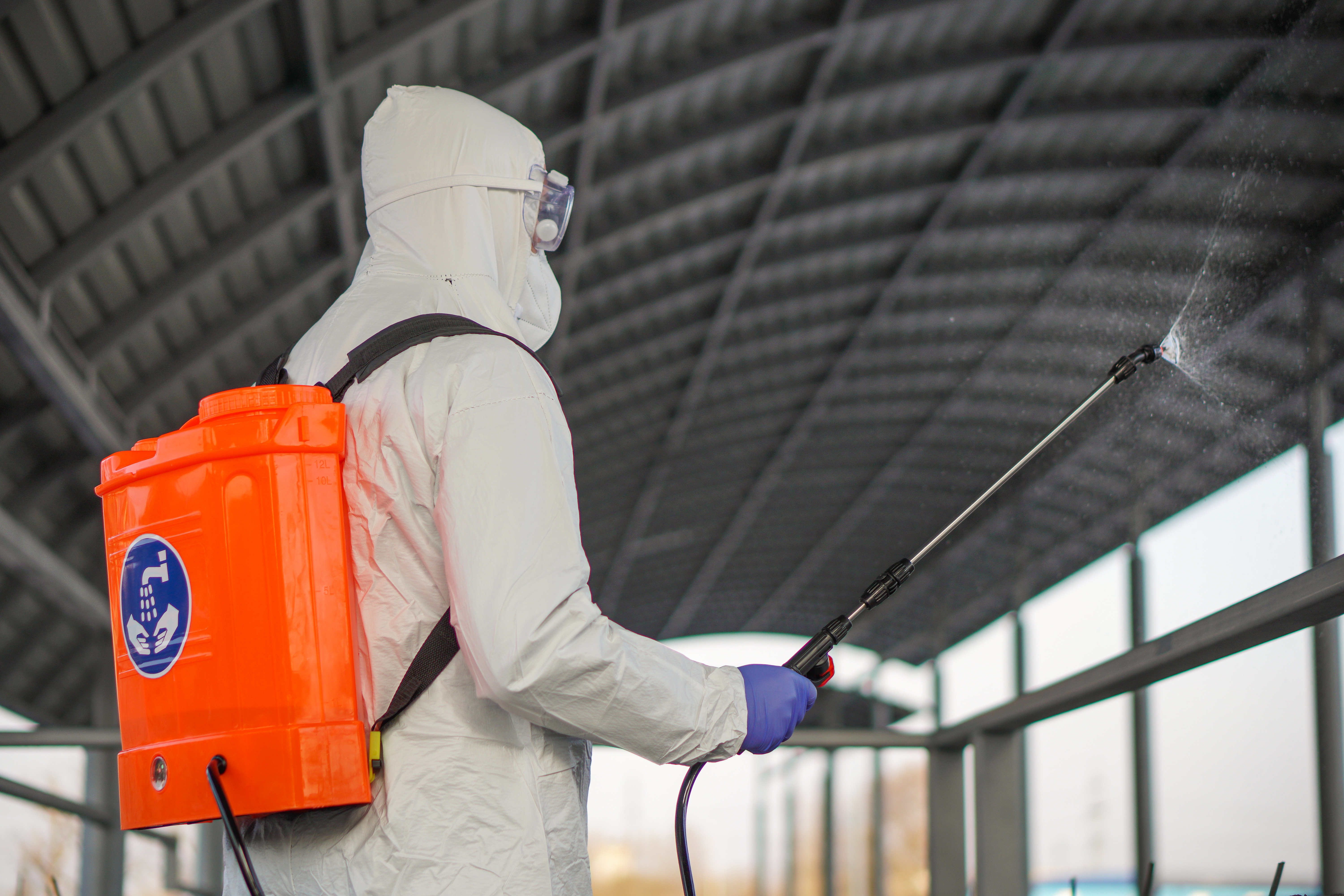 Person in protective suit desinfecting a barn