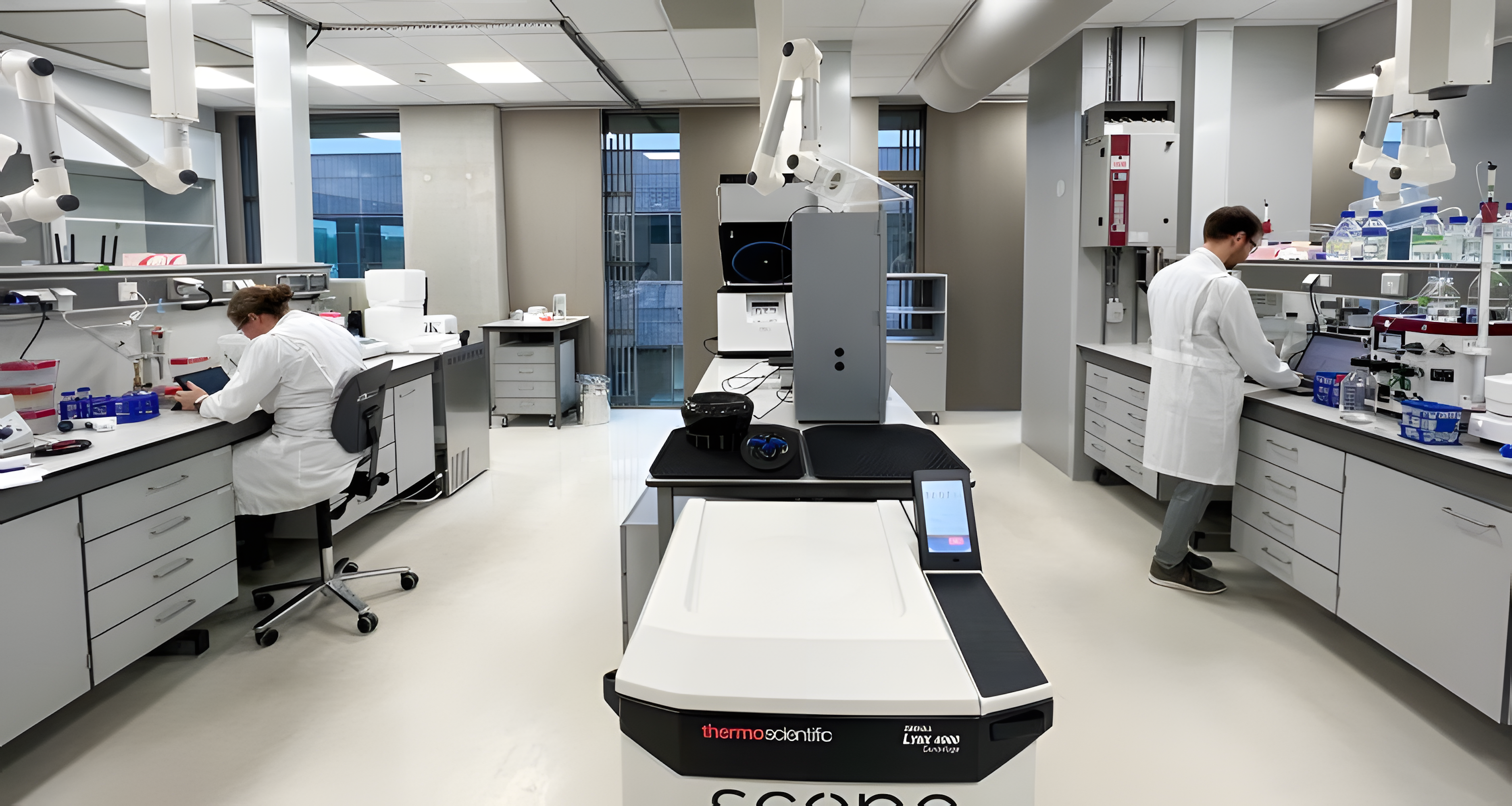 Two researchers stand on either side of each other working in the lab