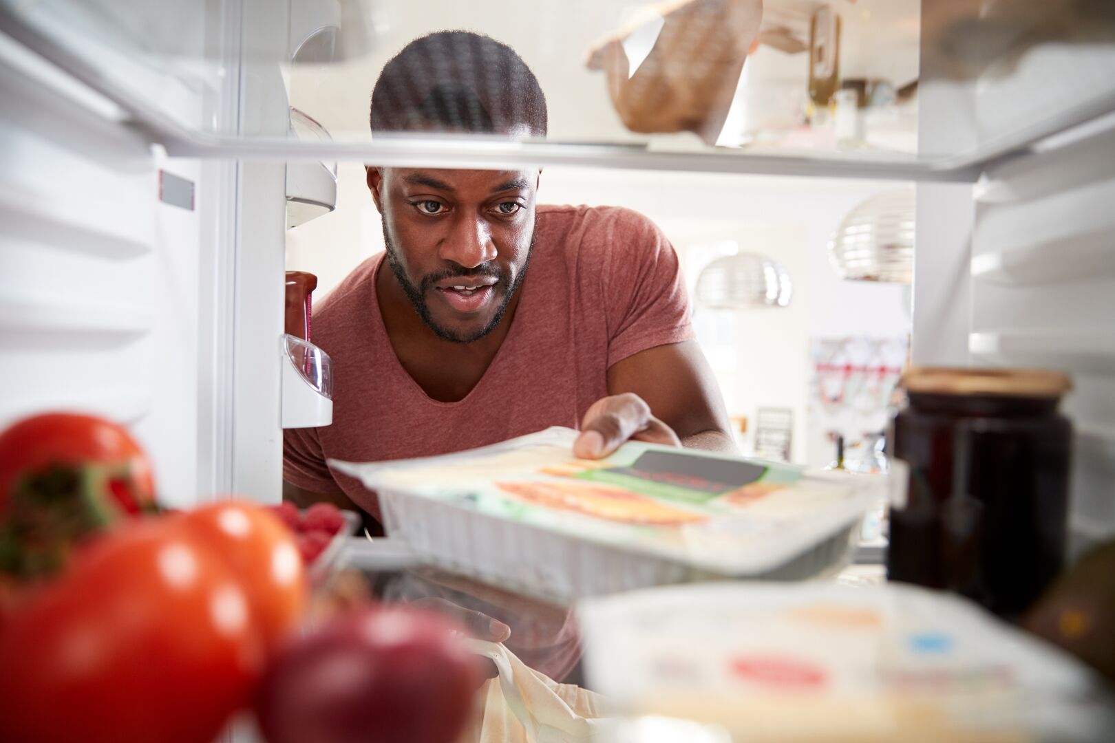 A man put packaged food in the refrigerator