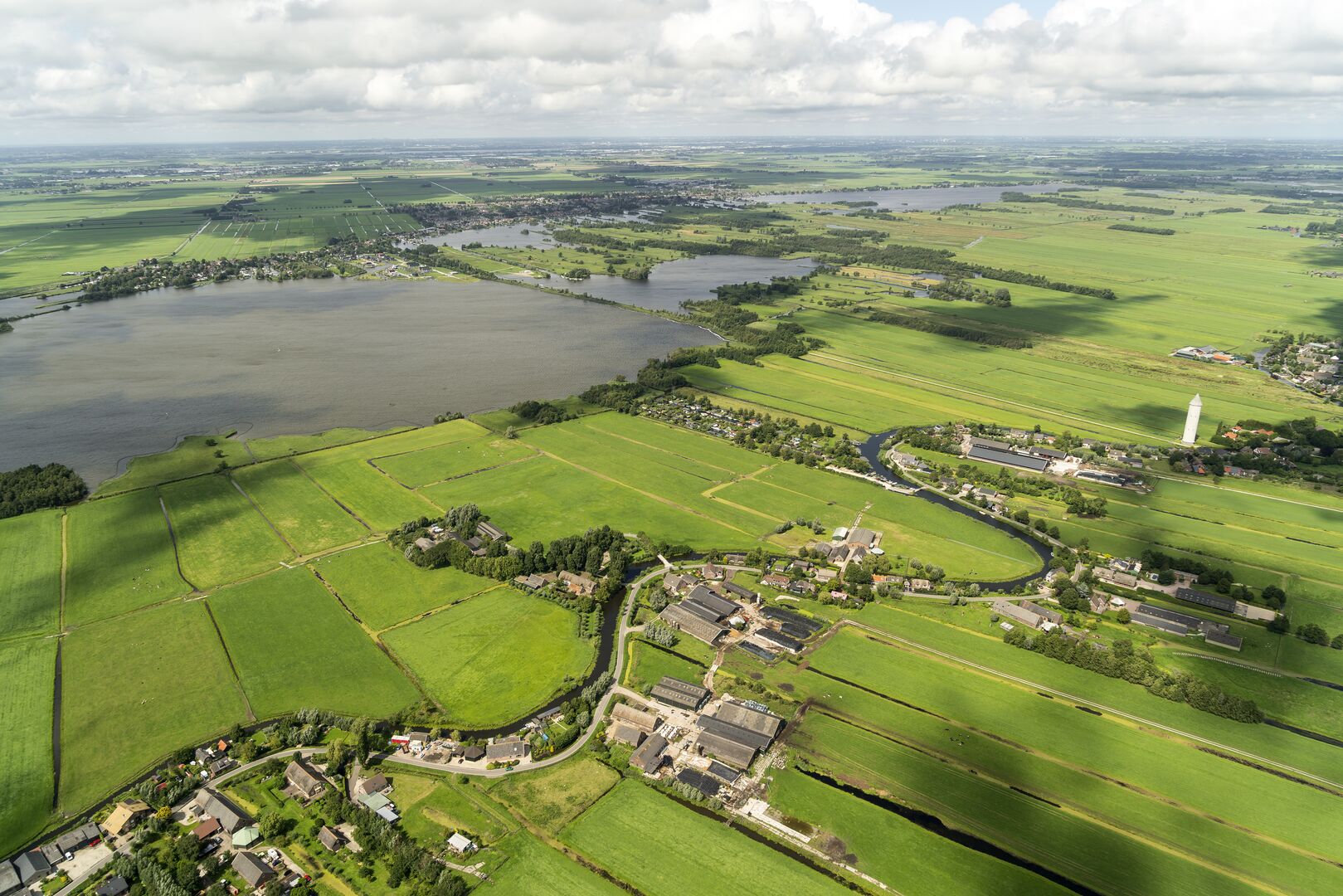 Een luchtfoto van een typisch Nederlands landschap met weides en water