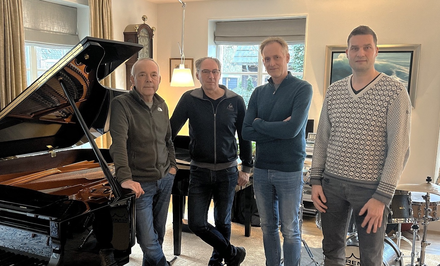 De bandleden van GoGo-Pigeons naast een pianovleugel