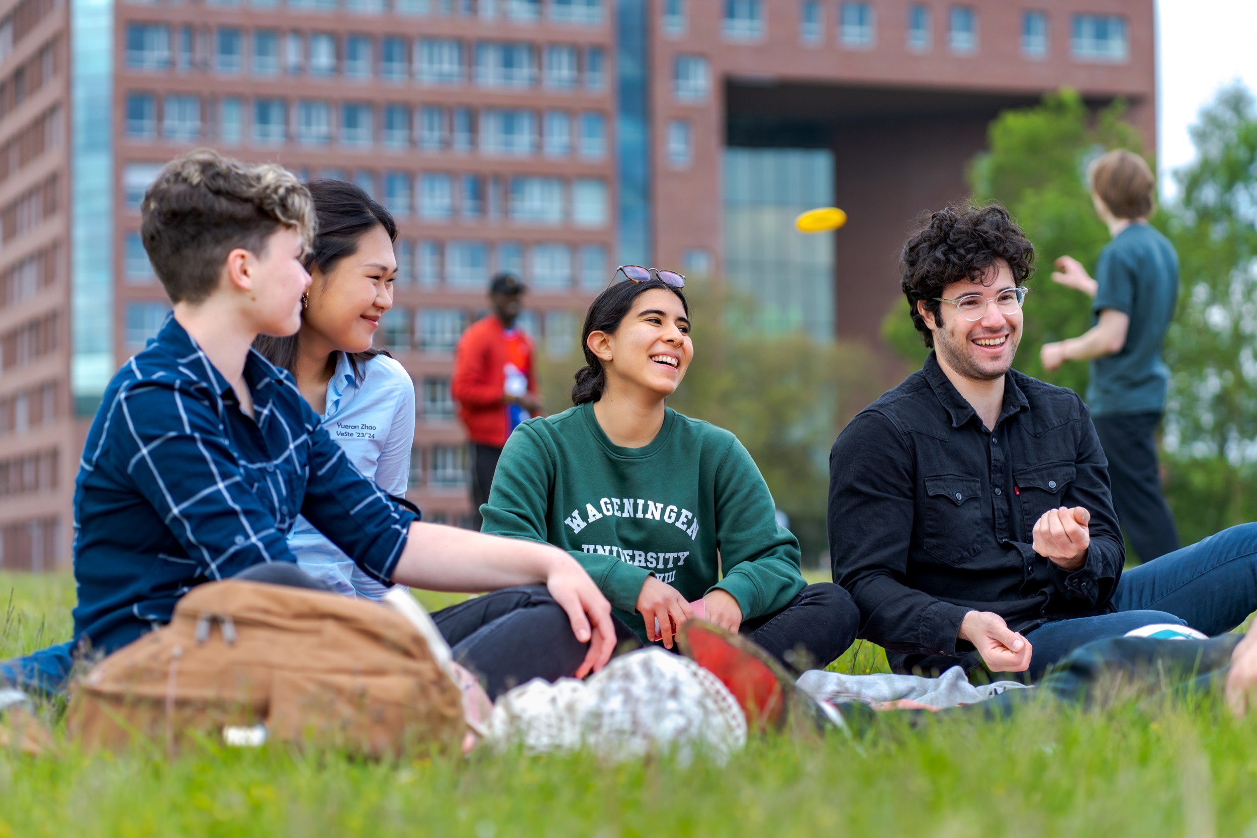 Studenten zitten in het gras op de campus