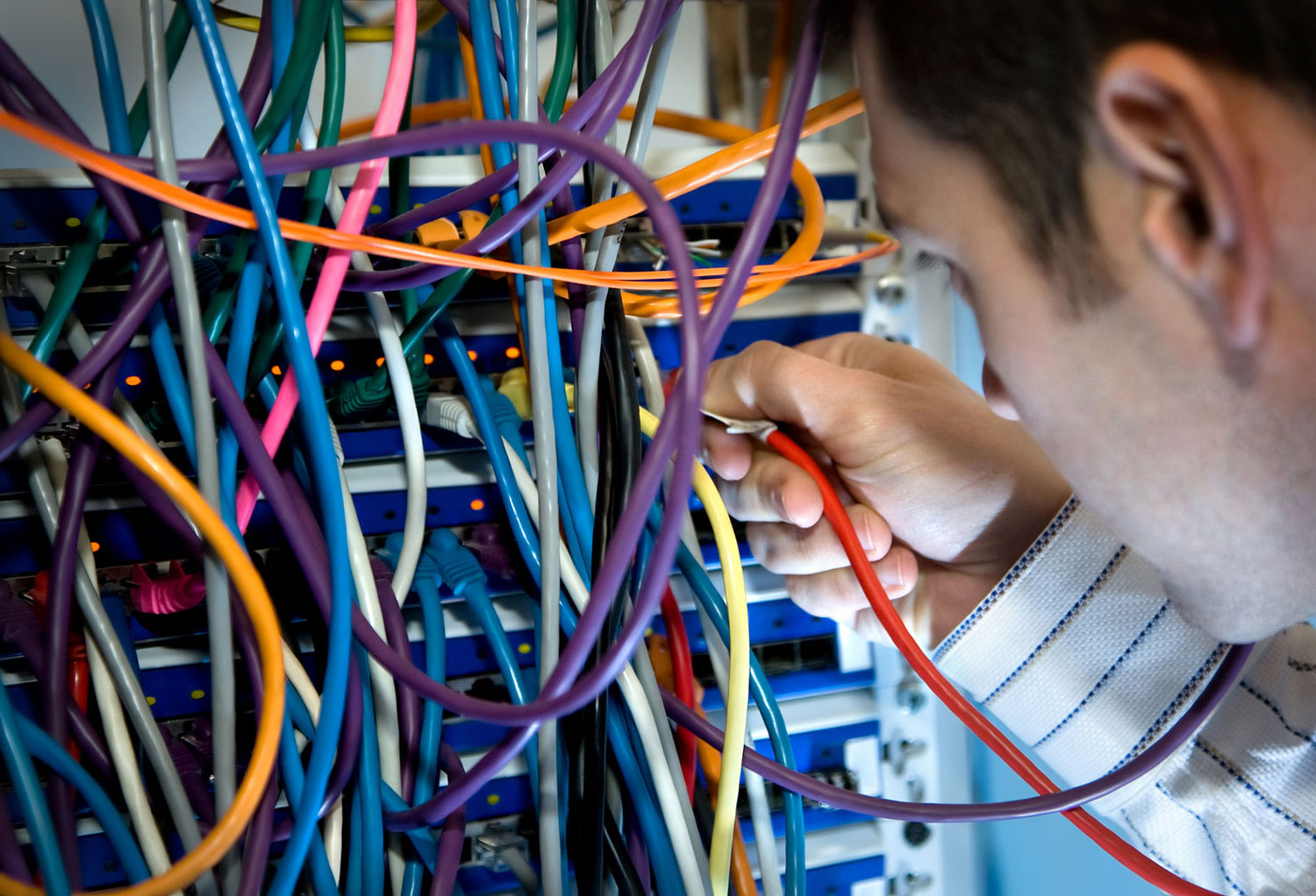 Een IT-medewerker kijkt naar kabels in een server