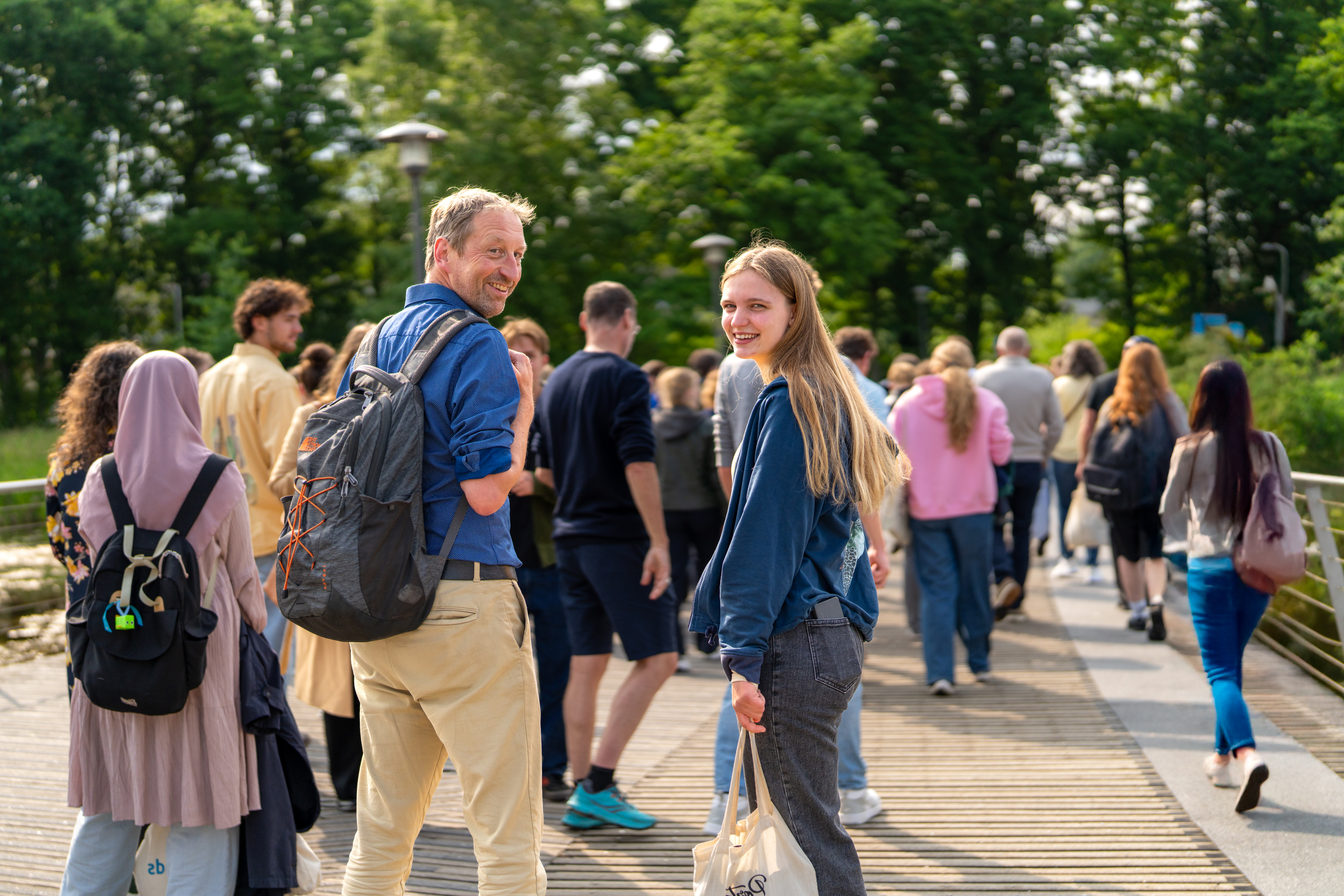Studenten en een ouder lopen over een brug.