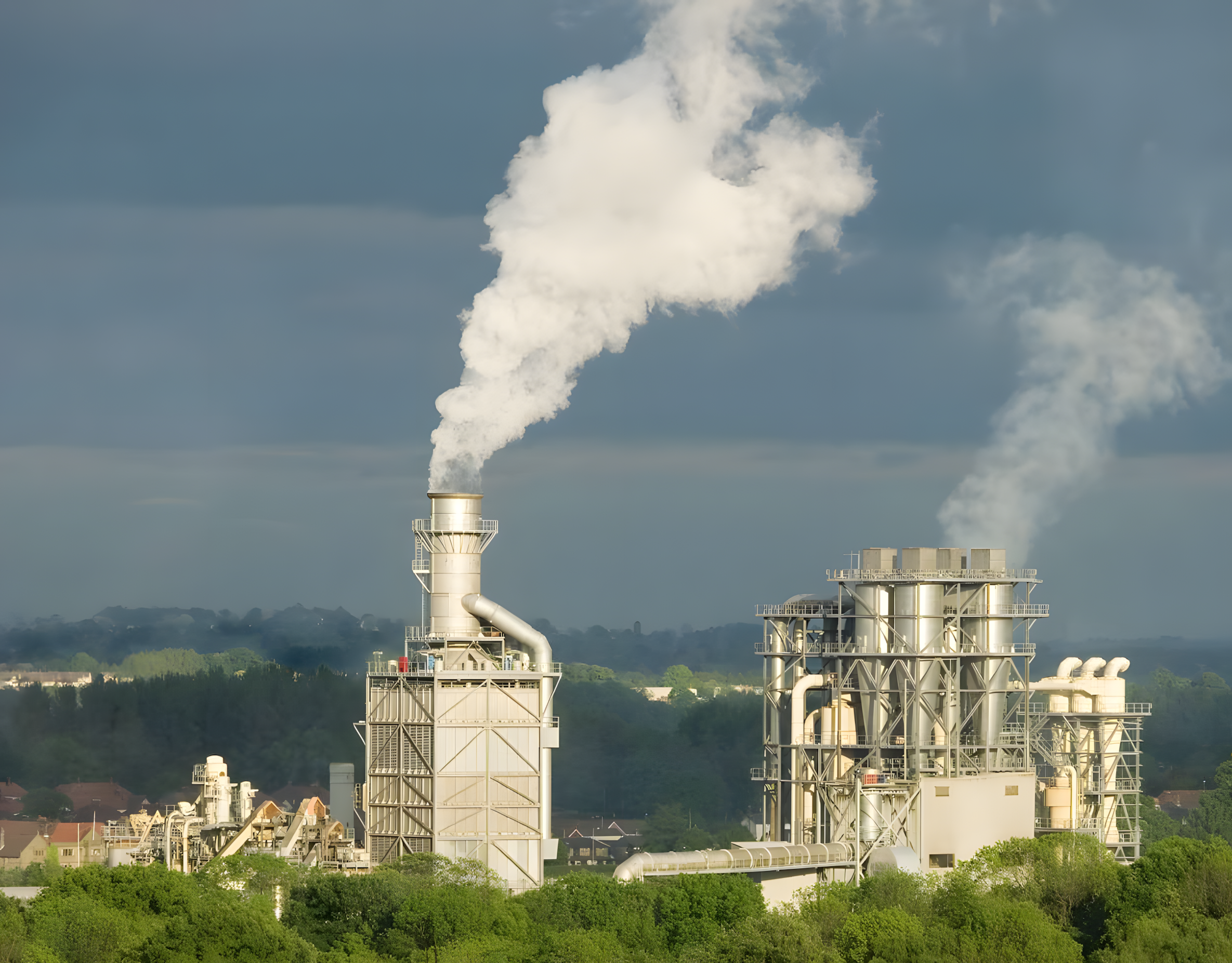 Plumes of smoke arise out of two chimneys between the trees