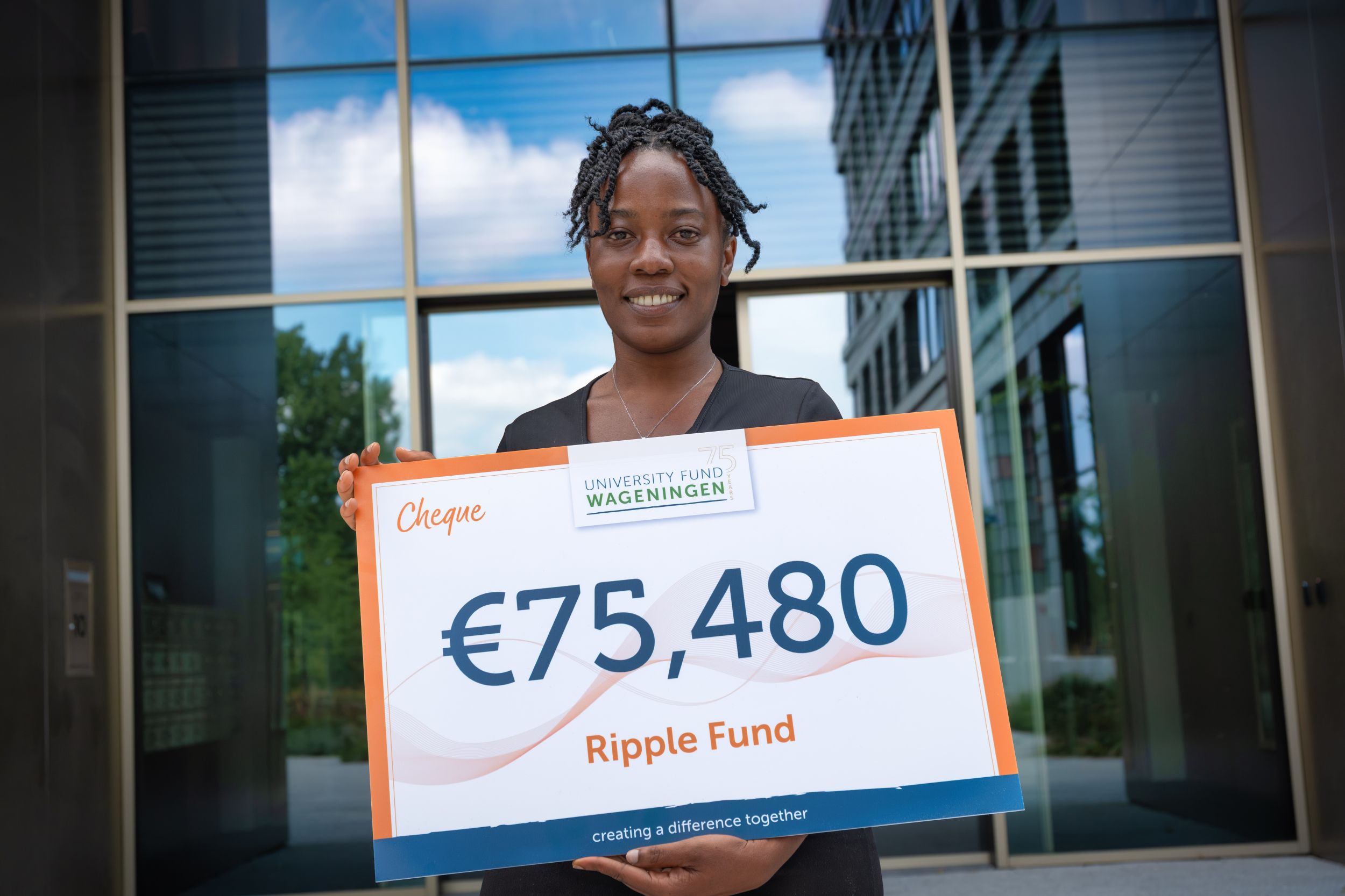 Elisabeth Obeng houdt een cheque vast van €25.480 voor het Ripple Fund