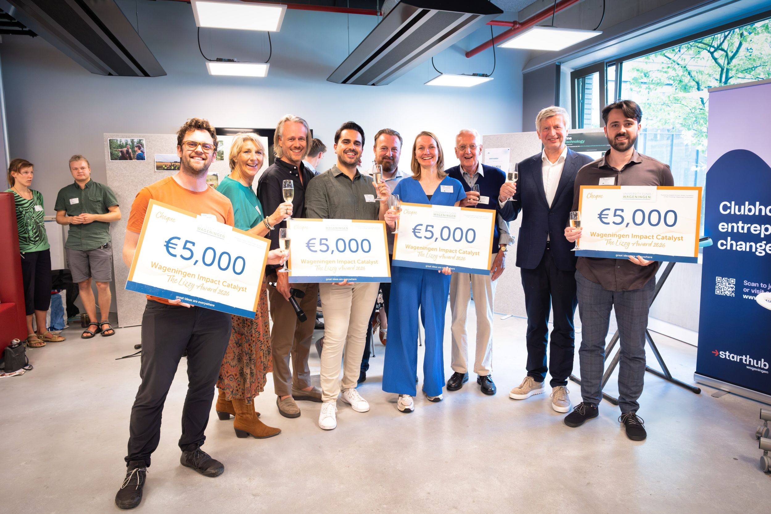 Een groep van tien mensen met champagneglazen en vier cheques