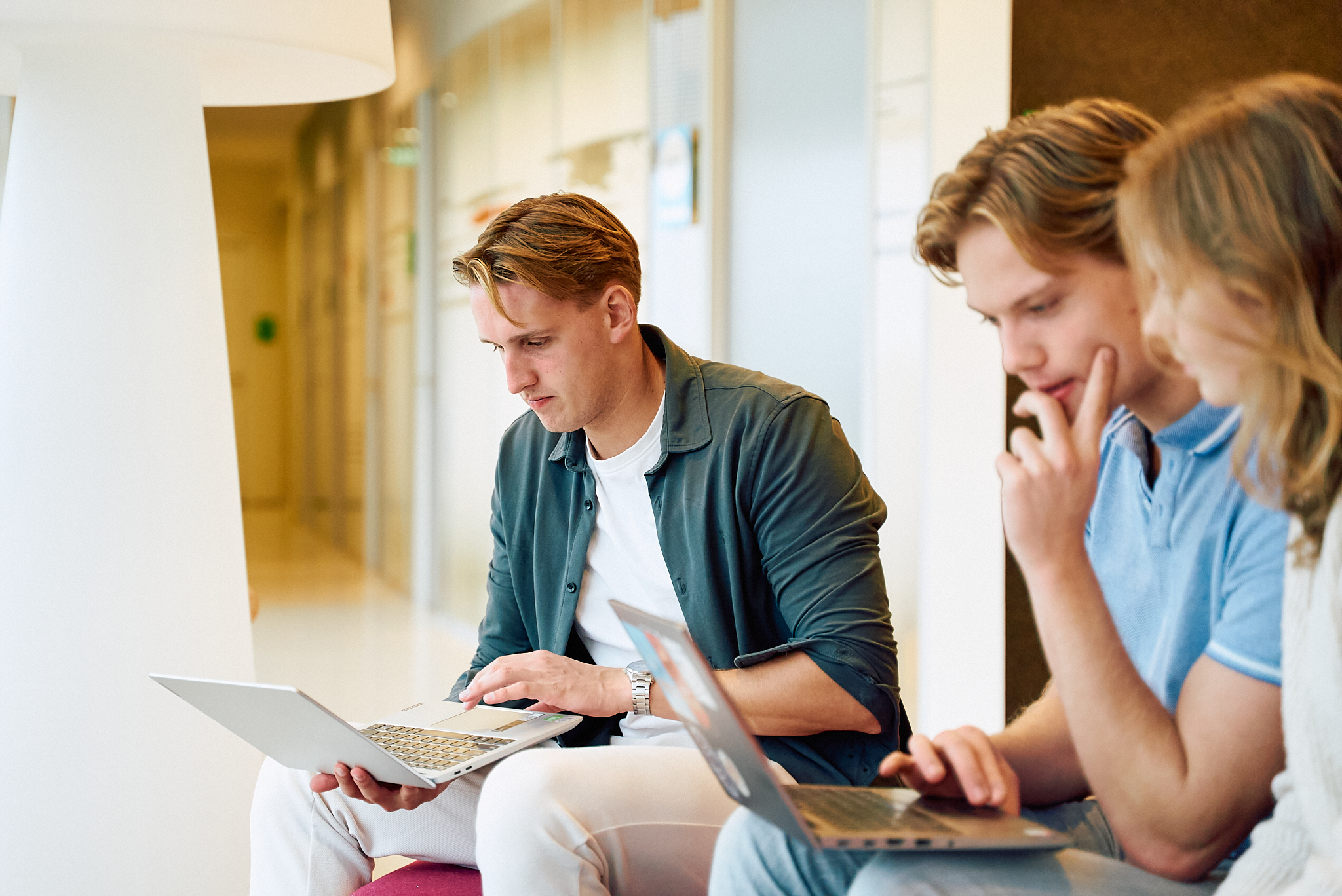 drie studenten zitten met laptop op schoot
