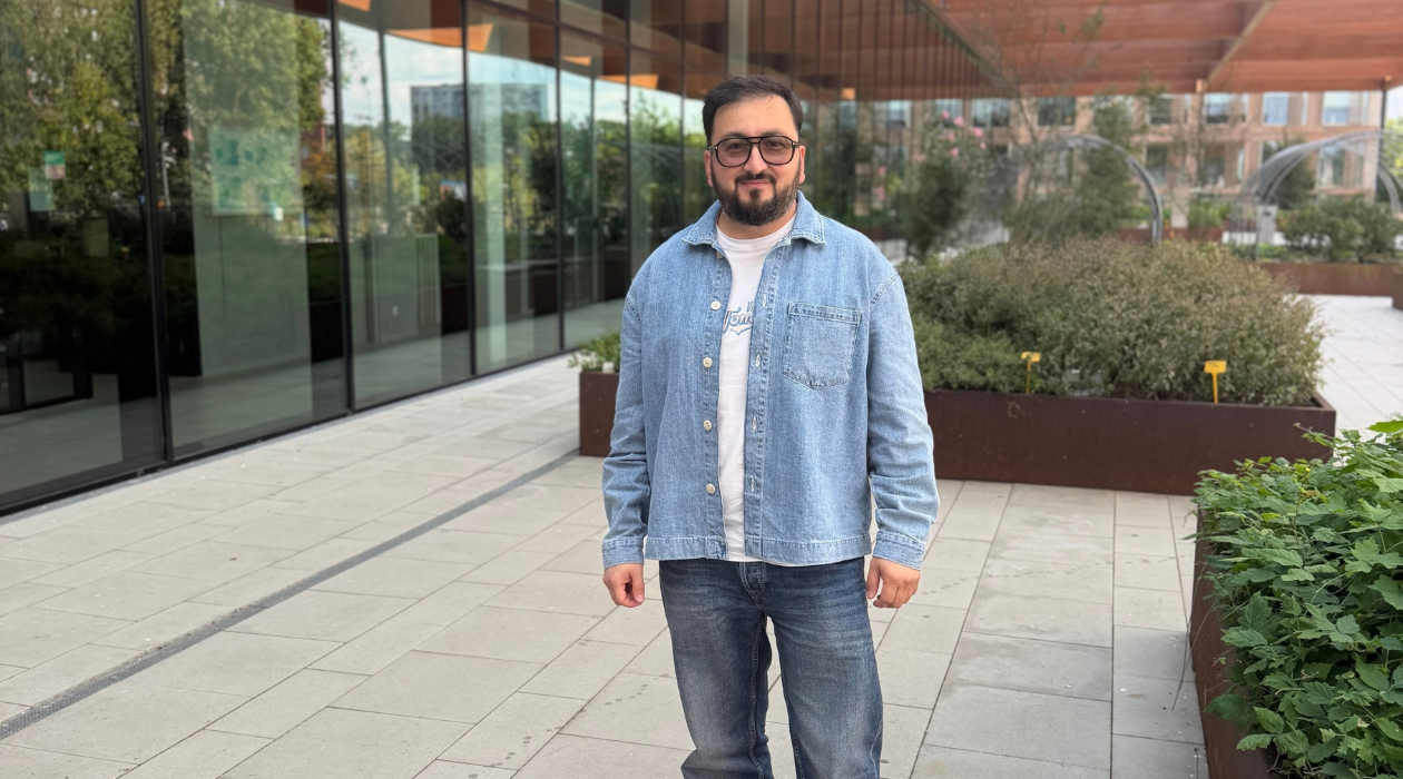 man with jeans jacket in front of green building