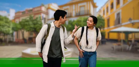 Two young people talking with a Spanish city in the background