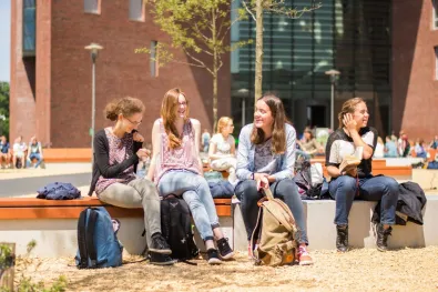 Studenten zitten voor gebouw op de campus