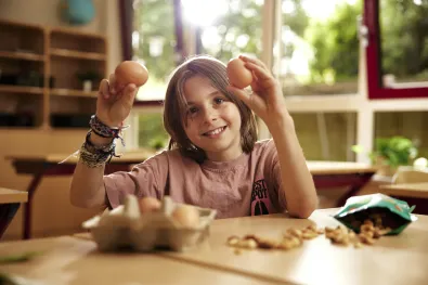 Jongen houdt eieren omhoog in de klas.