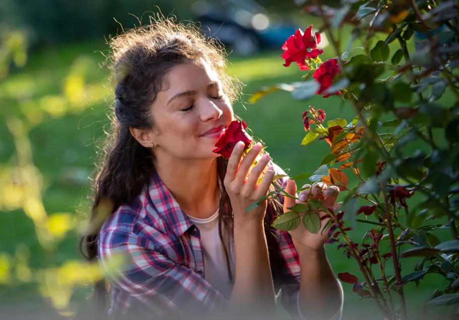 Jonge vrouw die bloemen ruikt in een tuin