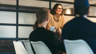 Group of colleagues engages in a discussion. A woman leads the team, presenting ideas to colleagues.