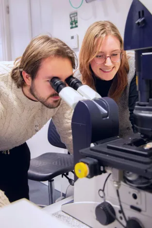 Two students behind a microscope
