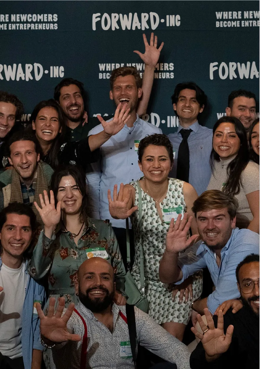 A group of many people happily stand in front of a Forward Inc sign