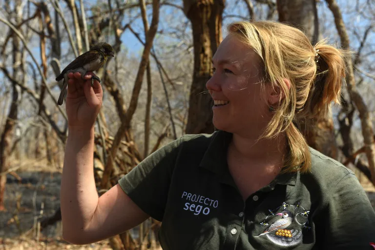 A portrait of Jessica van der Wal with a honeyguide bird on her hand