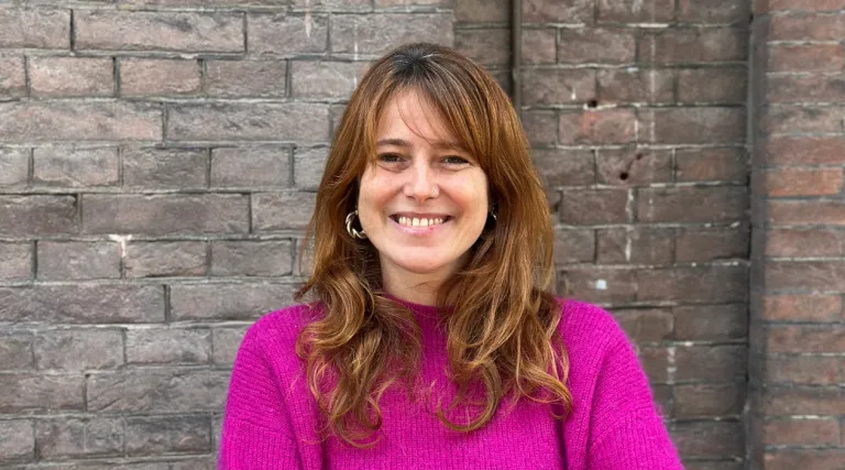 woman in pink sweater in front of brick wall