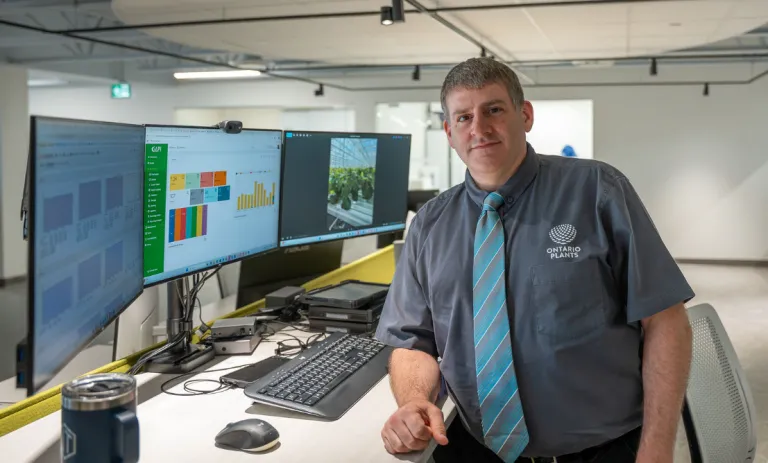 Greenhouse professional beside computer screens displaying crop and greenhouse data