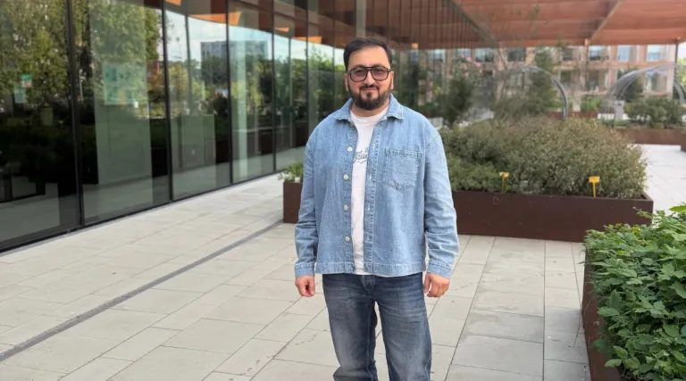 man with jeans jacket in front of green building