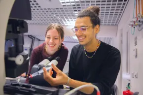 Two students behind a microscope